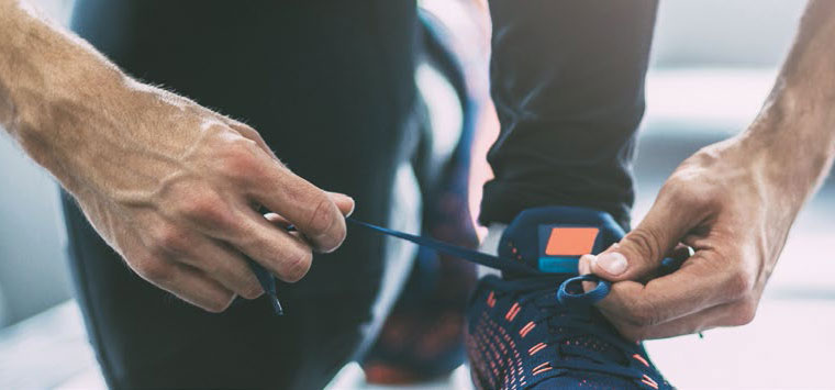 A man ties the shoelaces on his running shoes.