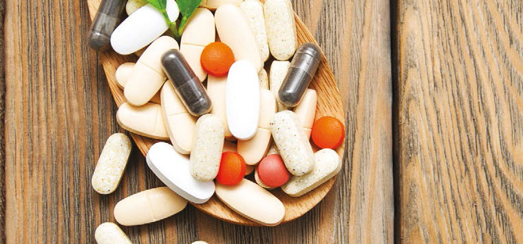 Some pills sitting inside a small plate on a wooden table.