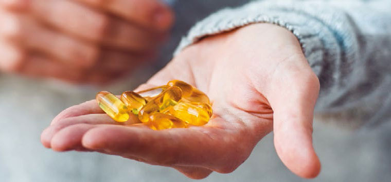 A woman holding a handfull of cod liver oil capsuals.