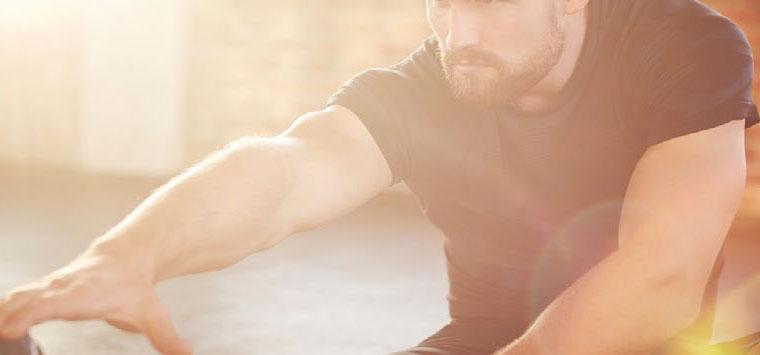 A man stretches in bright sunlight.