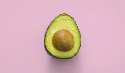An avocado, against a pink background.