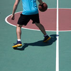 A man plays basketball on a sunny day.