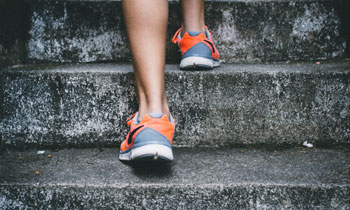 A woman wearing running shoes climbs steps
